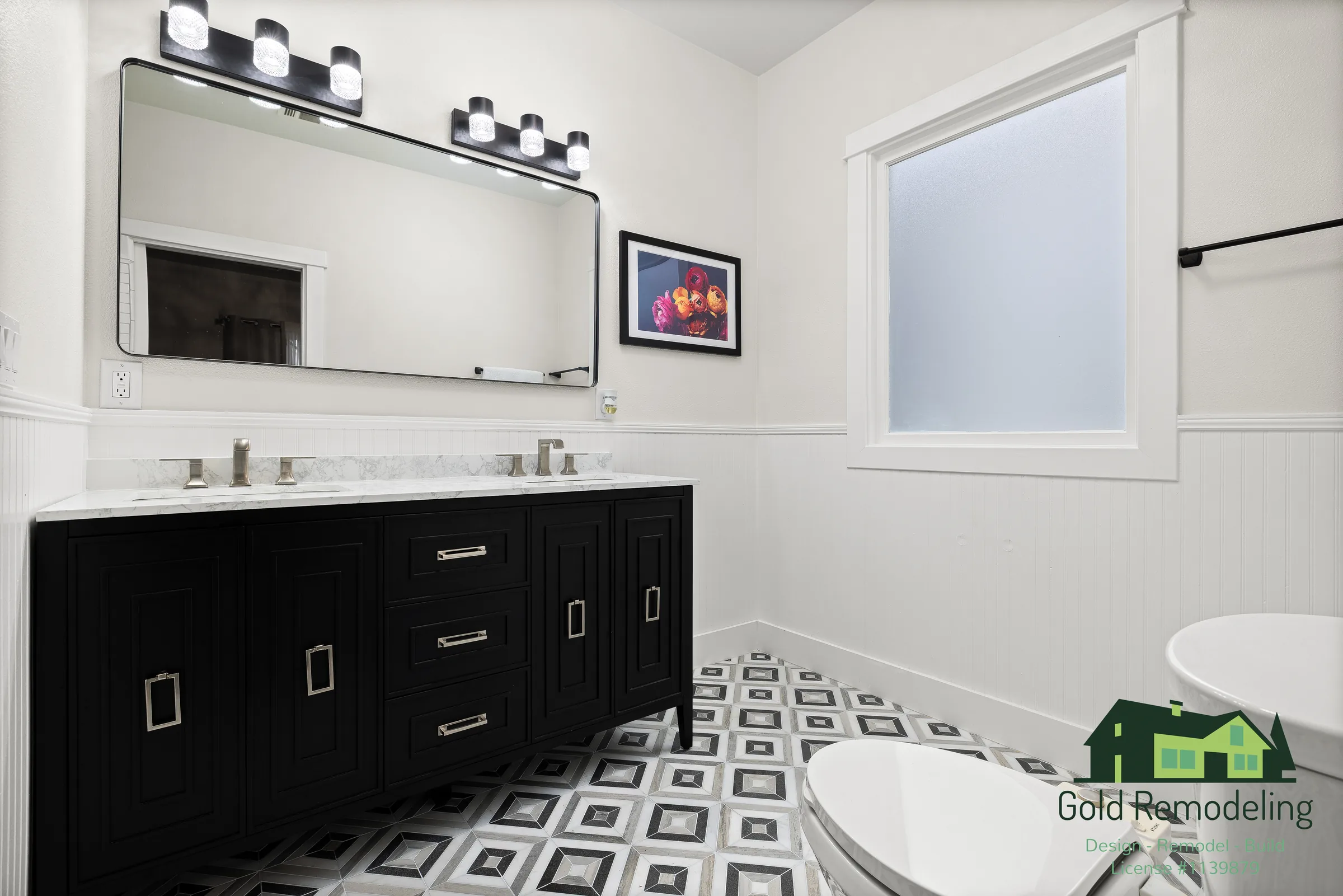 A refined bathroom remodel pairing a dark dual vanity with marble-look quartz counters, a glass walk-in shower, and a bold geometric tile floor.